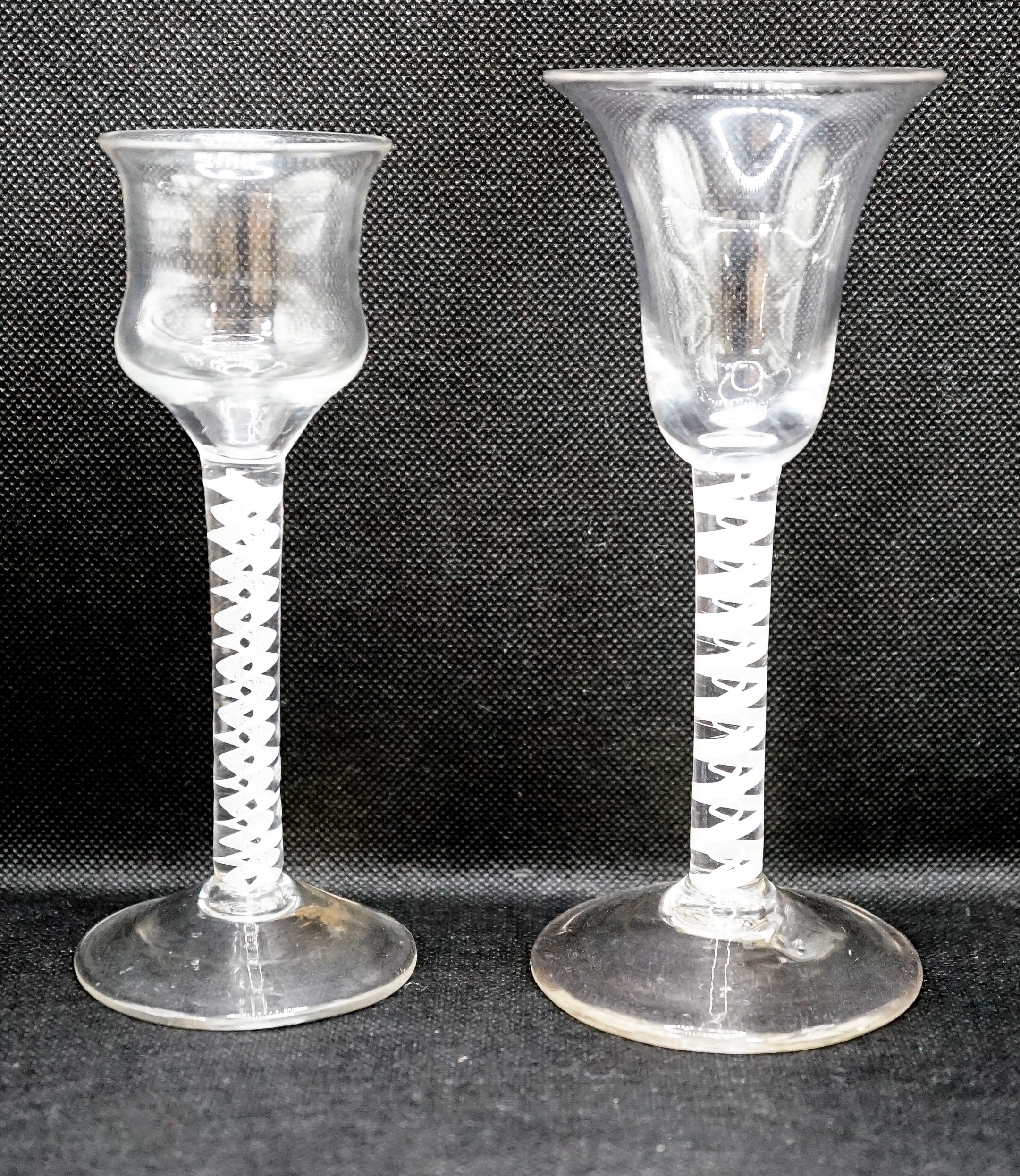 Two George III opaque twist stem cordial glasses, c.1760, each with a double series opaque twist stem, one with a bell shaped bowl the other with an ogee shaped bowl, 15 & 16cm